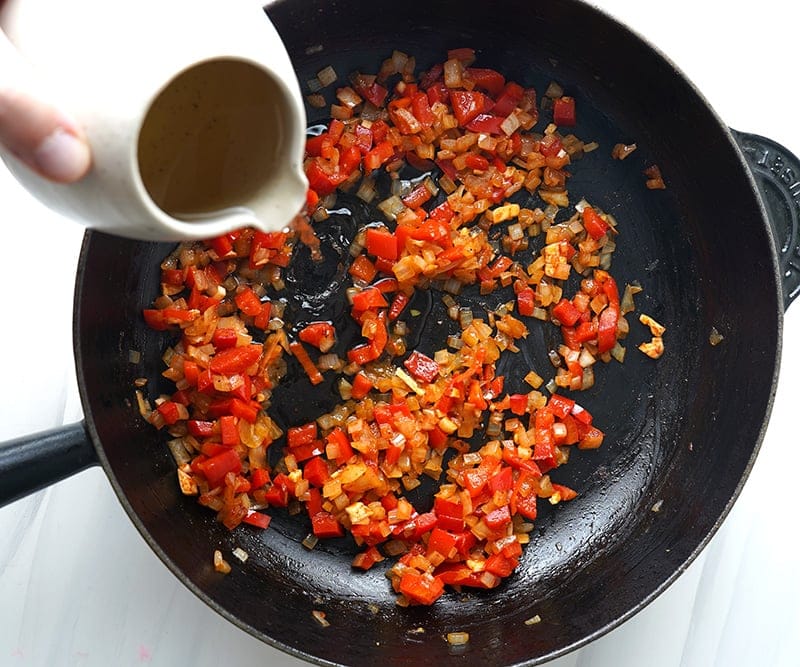 Adding wine to Spanish sofrito with onions and pepper