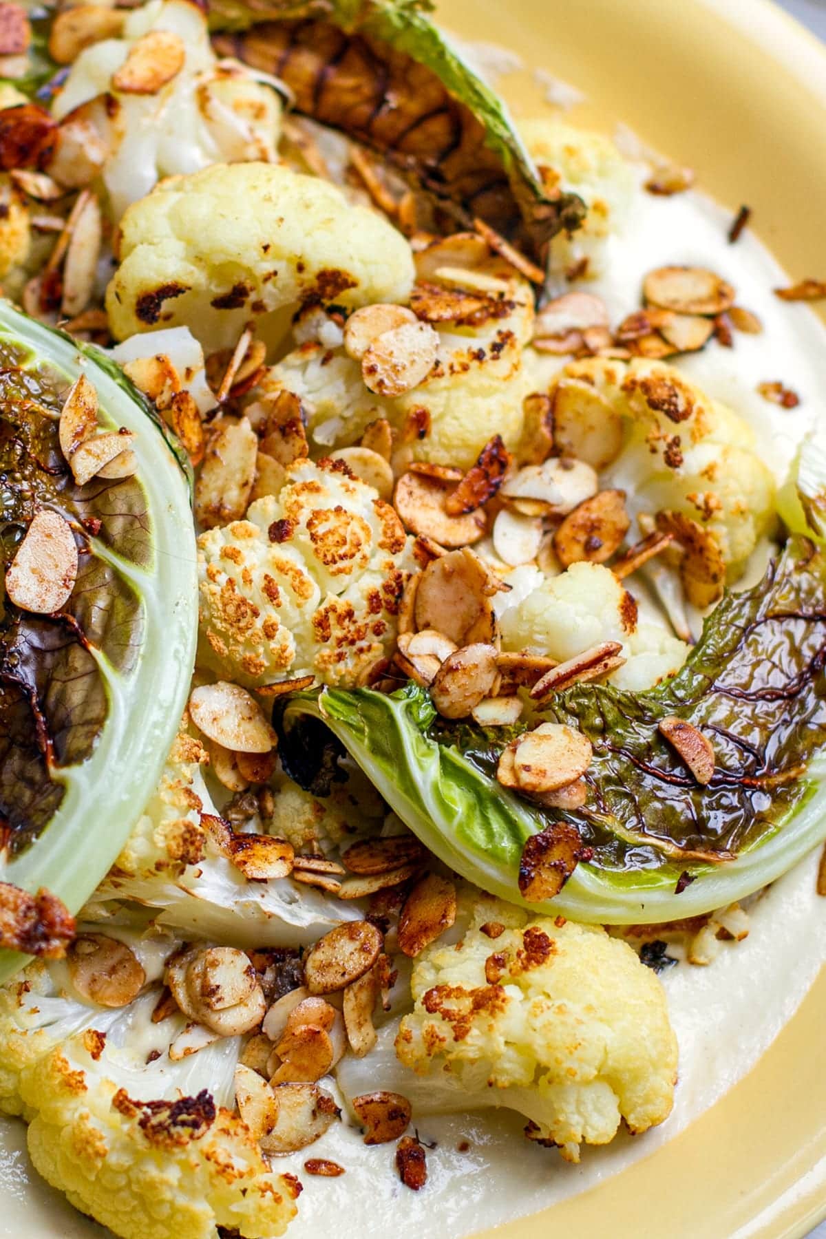 Roasted cauliflower with white sauce made out of cashews, nutritional yeast and garlic, topped with toasted almonds