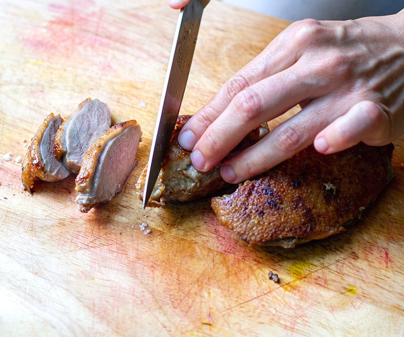 Slicing duck breast on a chopping board