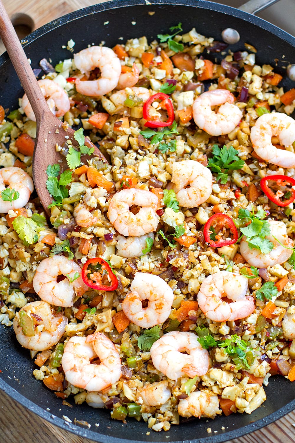 cauliflower shrimp fried rice in a skillet with a spatula
