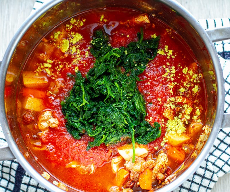 Chicken stew with tomatoes and spinach in a pot