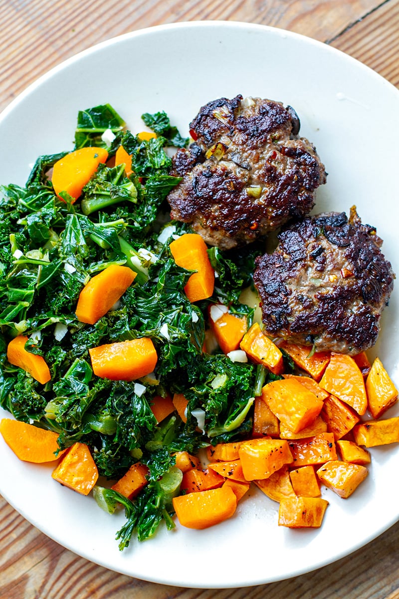 Whole30 dinner of beef burgers with garlic kale and sweet potatoes