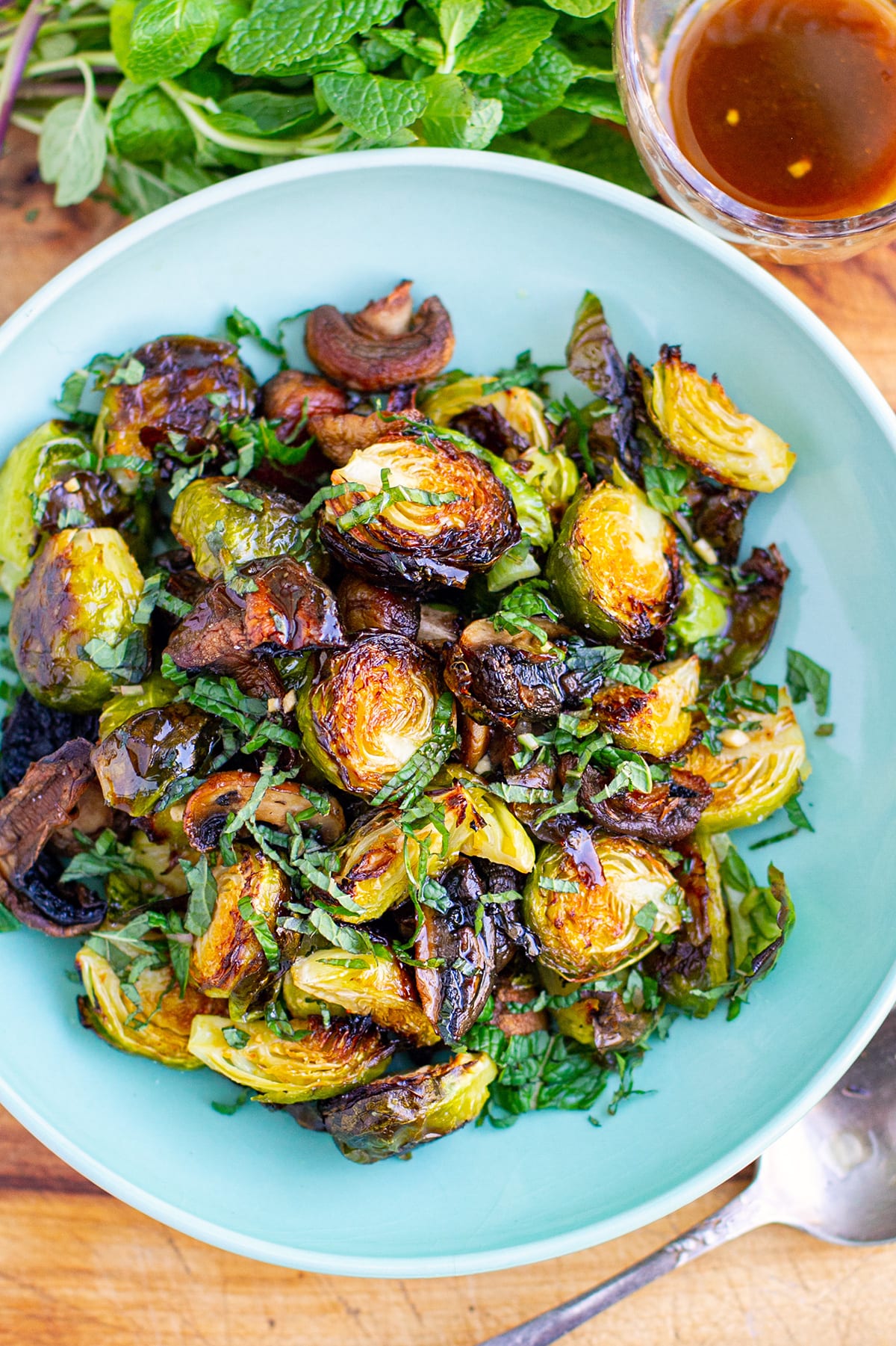 Roasted Brussel sprouts with Honey Balsamic Dressing in bowl with extra dressing on the side.