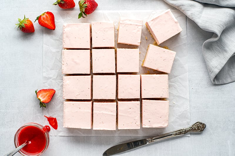 Sliced cheesecake bars with fresh strawberries