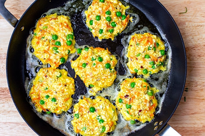 Pan-frying paneer fritters in a pan