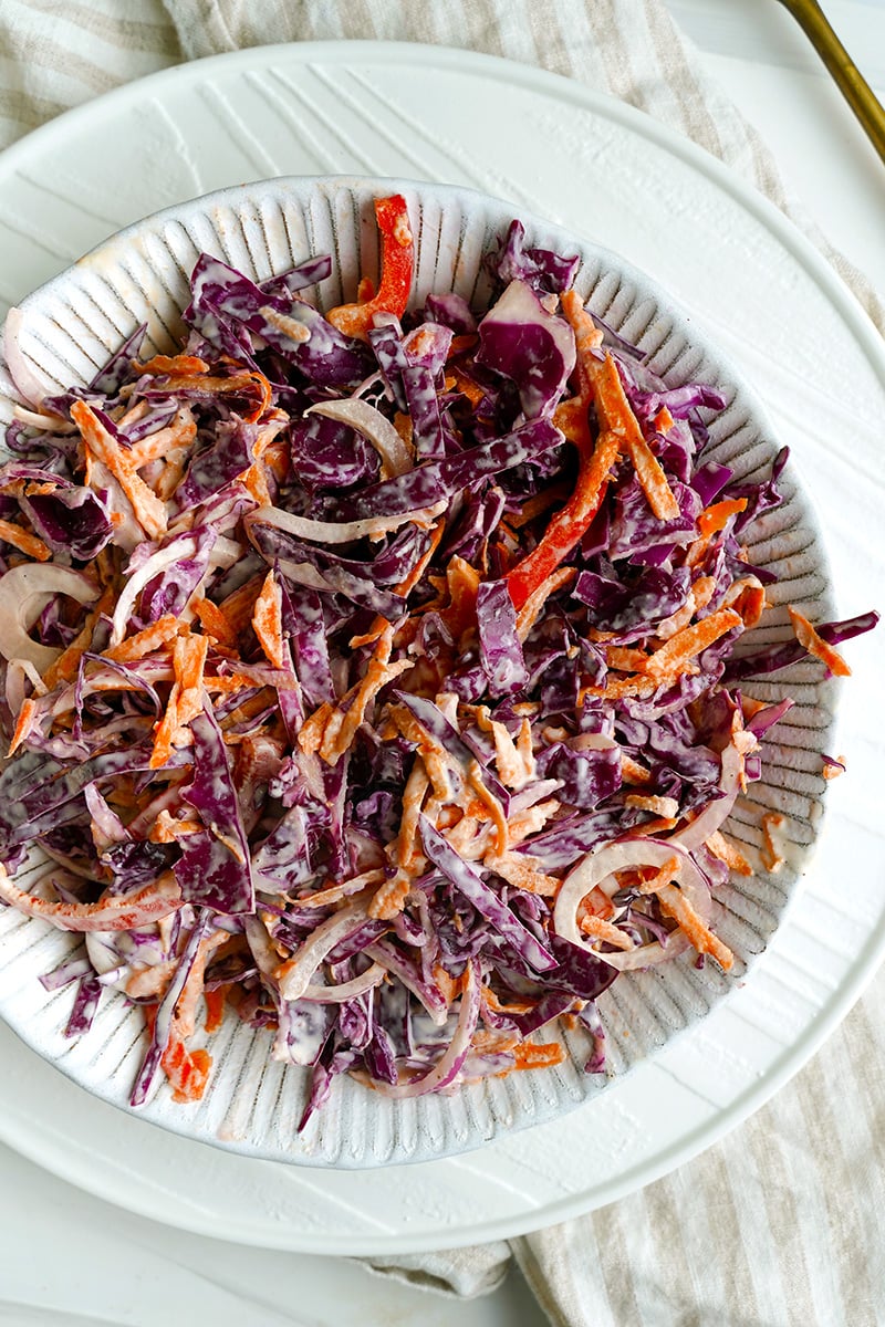 Creamy red cabbage coleslaw salad with grated carrots, red peppers and onions. Mayonnaise dressing for coleslaw.