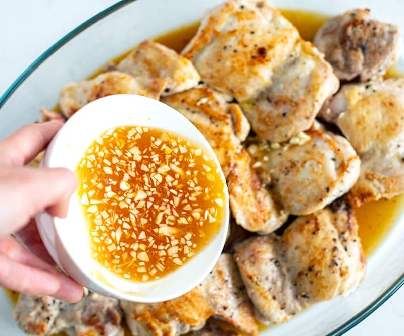 Chicken thighs in a baking dish with sauce going on top