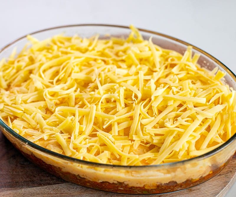 Cottage pie with ground beef, mashed potatoes and grated cheese in a casserole dish