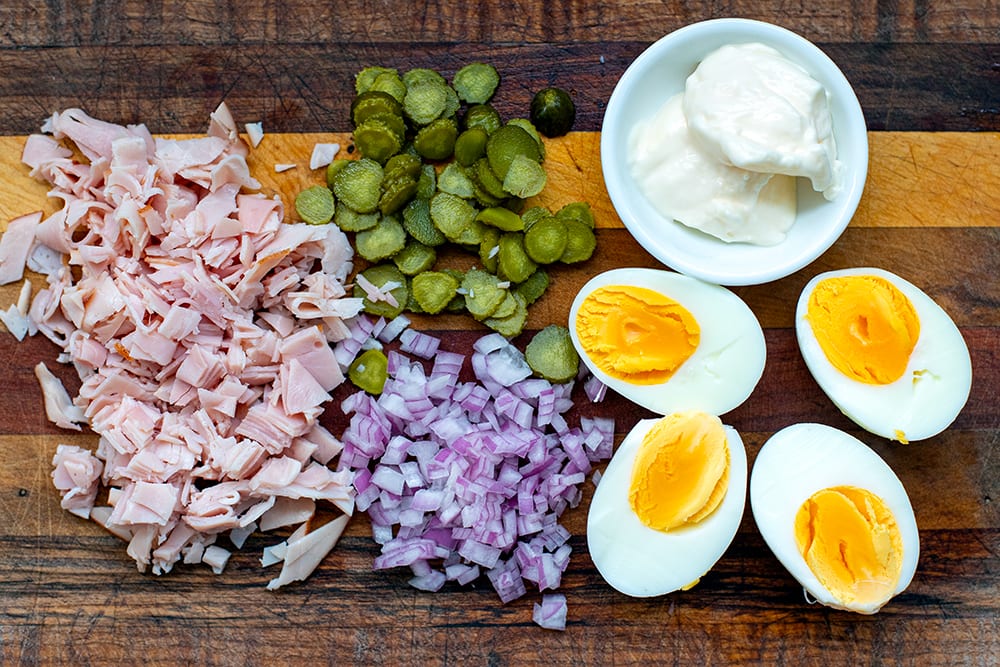 Egg salad ingredients: ham, pickles, onions, eggs and mayonnaise