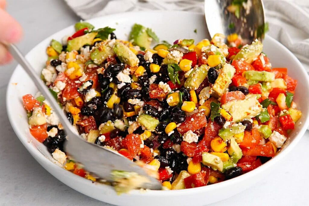 Making back bean, corn and avocado salad in a bowl