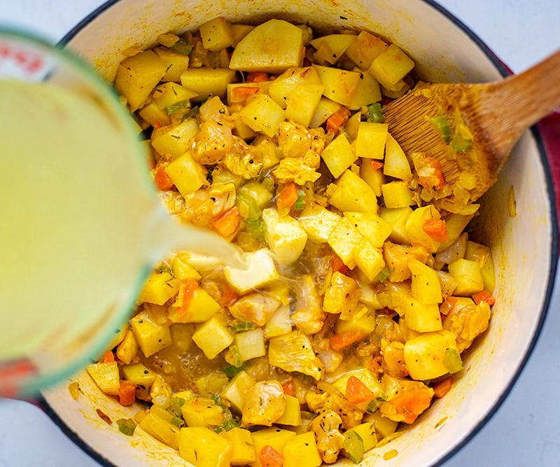 Adding chicken stock to the pot