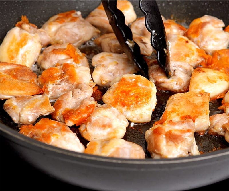 Fried chicken in pan getting turned