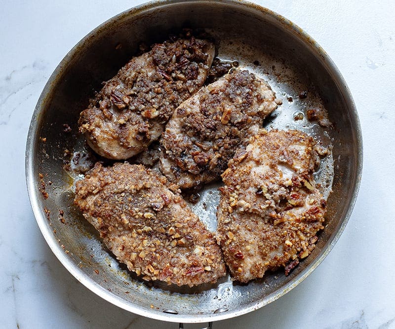 Fry pecan crusted chicken in skillet