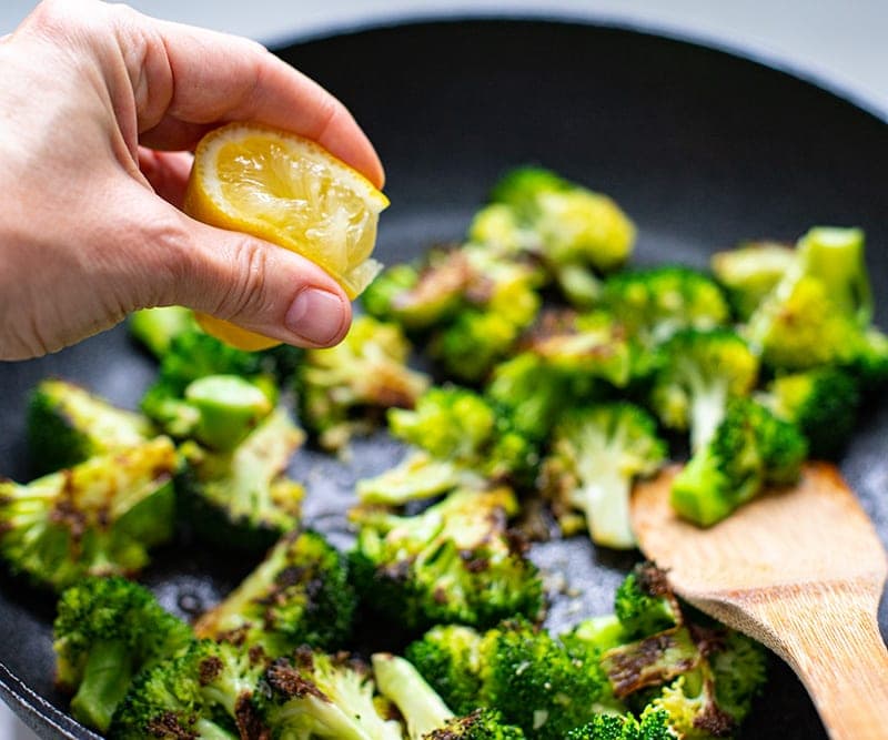 adding lemon juice to pan-fried broccoli