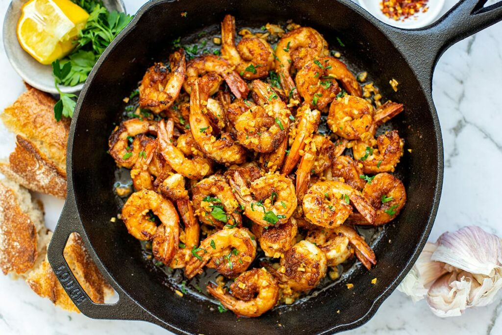 garlic prawns (shrimp) in a skillet with buttery sauce, lemon and parsley.