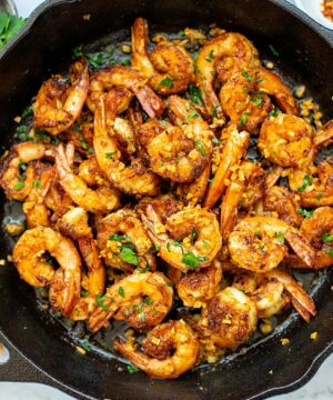 garlic prawns (shrimp) in a skillet with buttery sauce, lemon and parsley.
