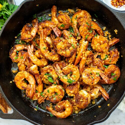 garlic prawns (shrimp) in a skillet with buttery sauce, lemon and parsley.