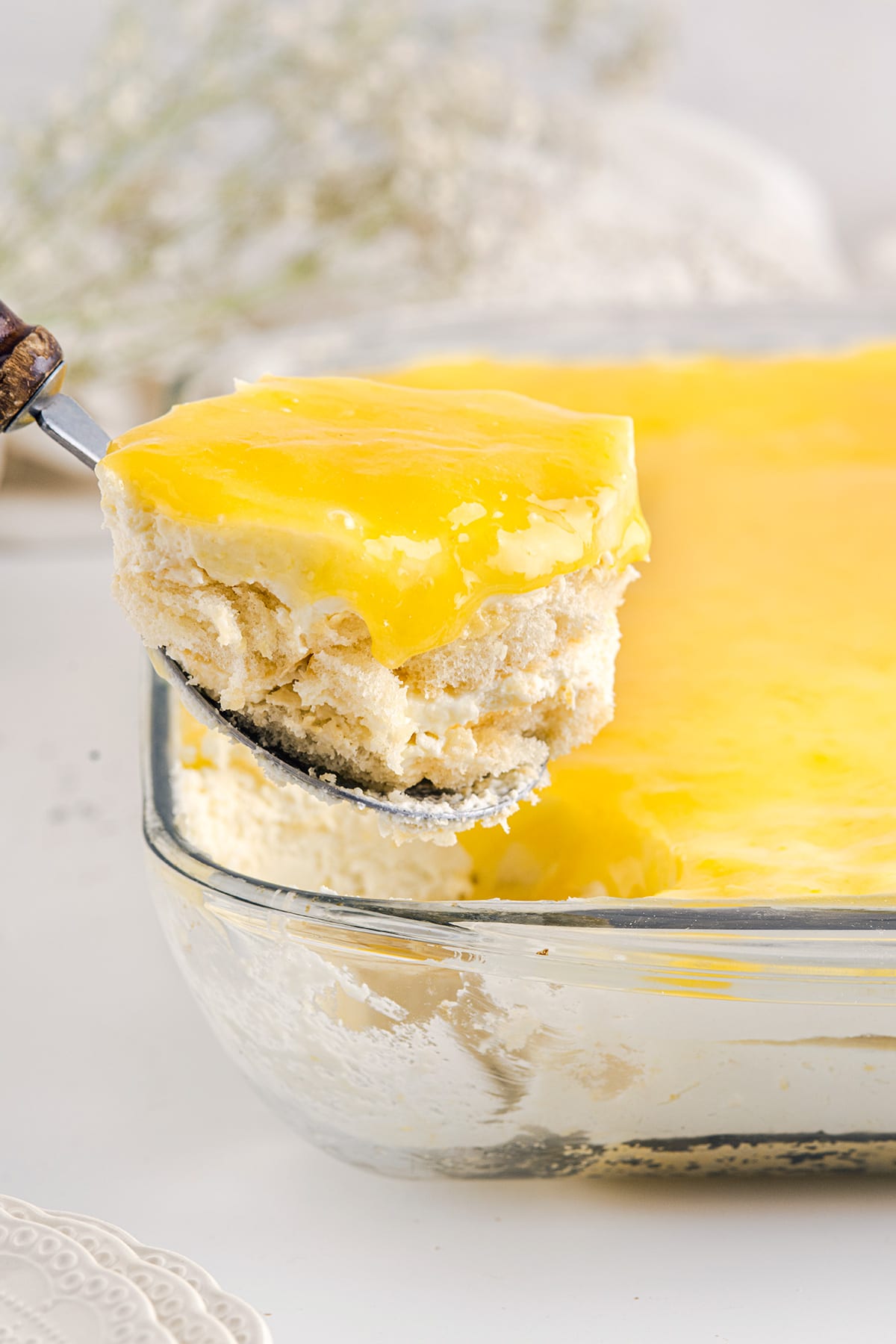Lemon tiramisu on a big serving spoon with sponge fingers soaked in limoncello, lemony cream filling and lemon curd.