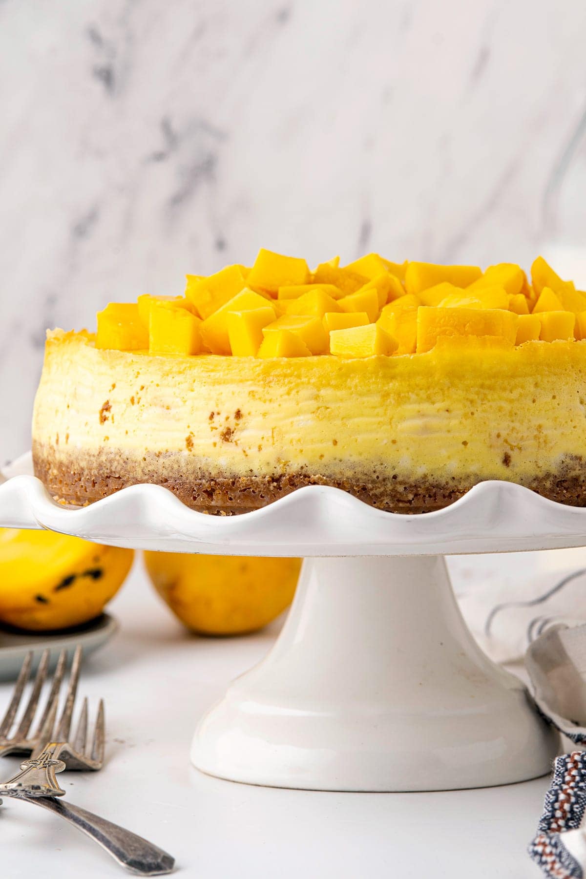 mango cheesecake on a stand with fresh mango topping.
