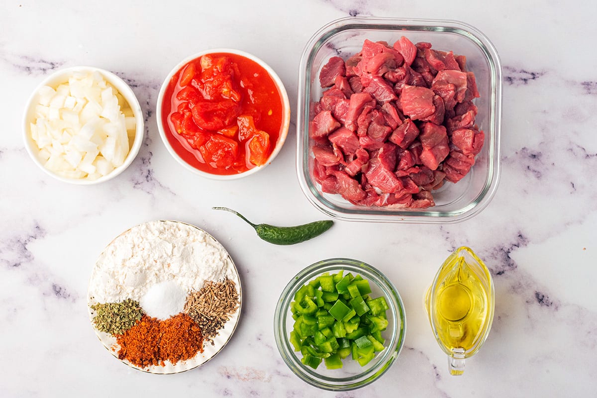 Ingredients for carne picada: beef, spices, bell peppers, tomatoes, onions, chile, olive oil