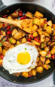 Country potatoes fried in a skillet with a fried on top