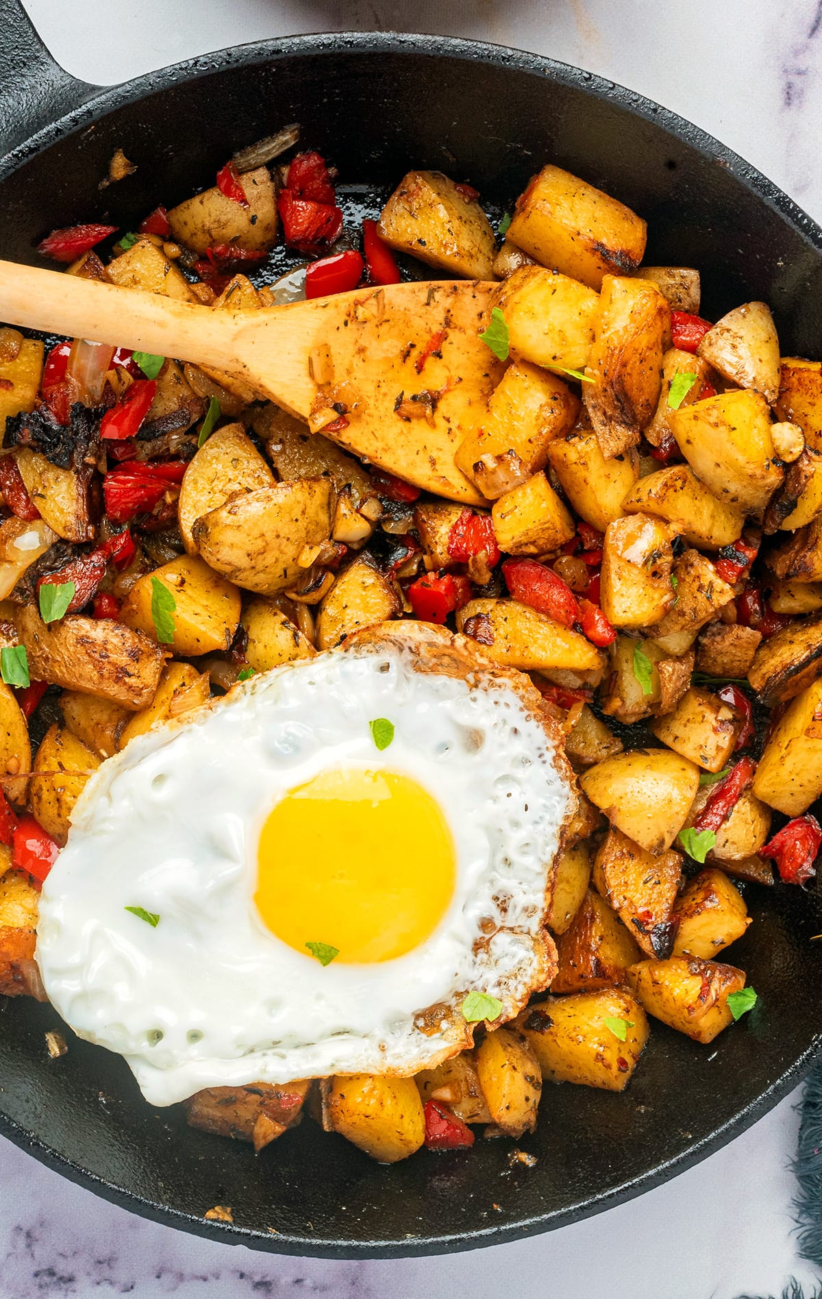 Breakfast potatoes fried in a skillet with a fried on top