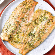 Baked rainbow trout with garlic butter and herbs on a plate horizontal image feature