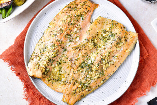 Baked rainbow trout with garlic butter and herbs on a plate horizontal image feature