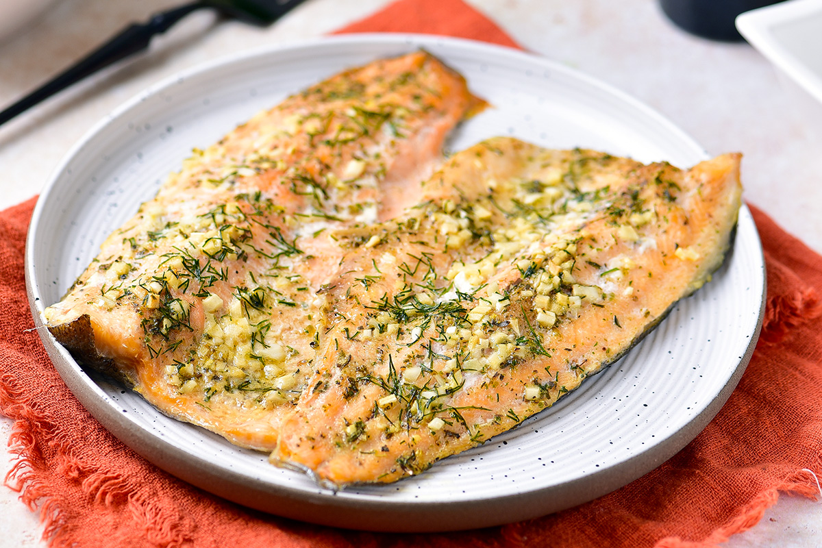 Baked trout with herbs and garlic butter on a plate