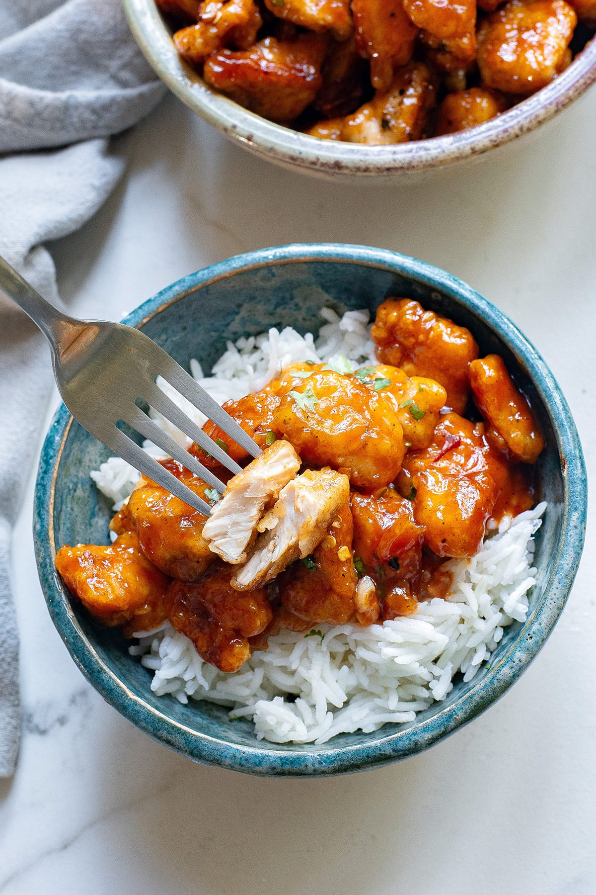 Sriracha honey chicken in a bowl with rice and a fork