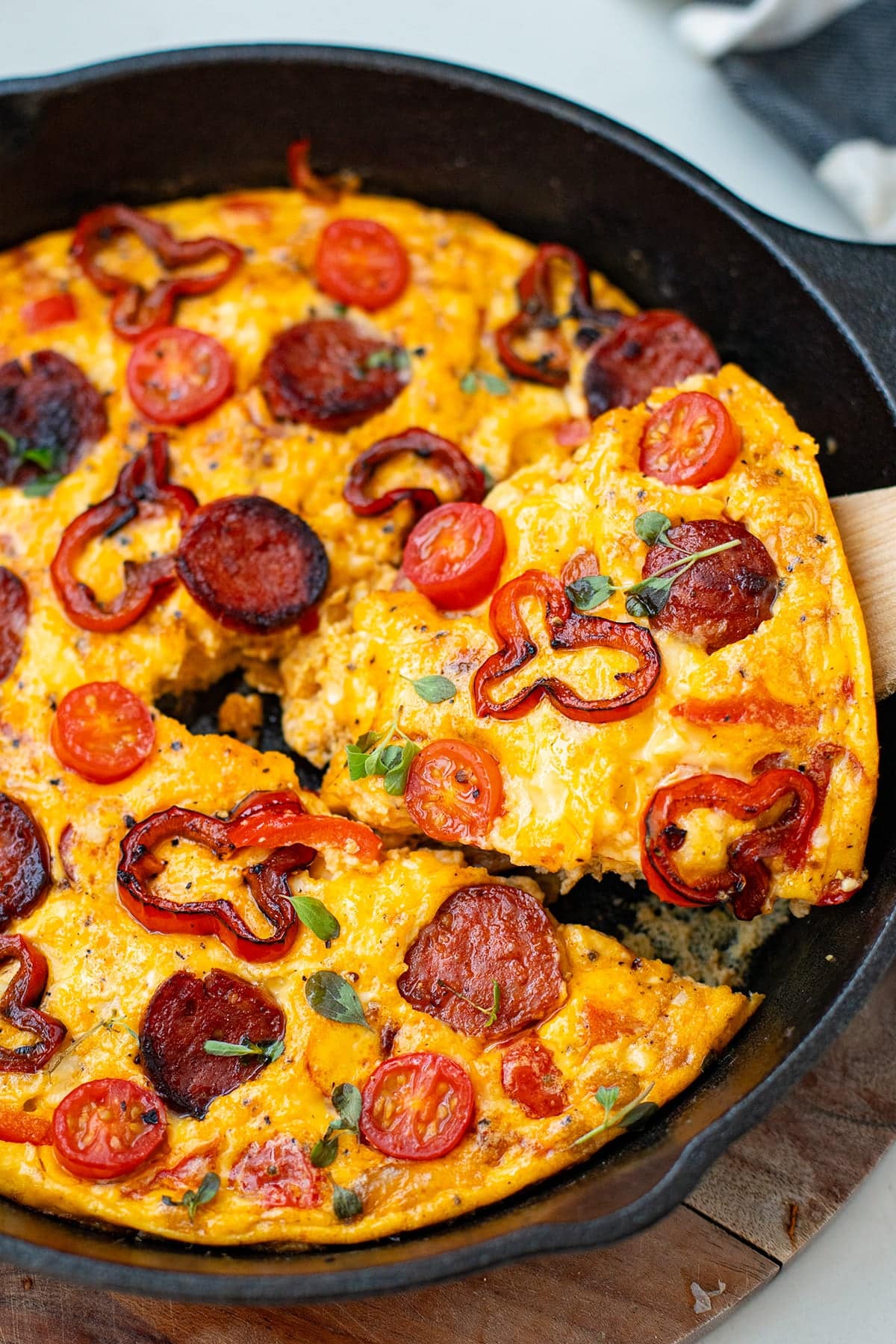 Chorizo Frittata in a cast iron skillet with a slice being taken out
