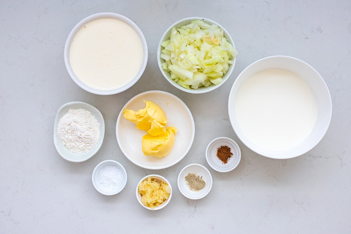 Ingredients for white gravy including salted butter, onion, garlic, milk, all-purpose flour, half and half, salt, pepper, and nutmeg