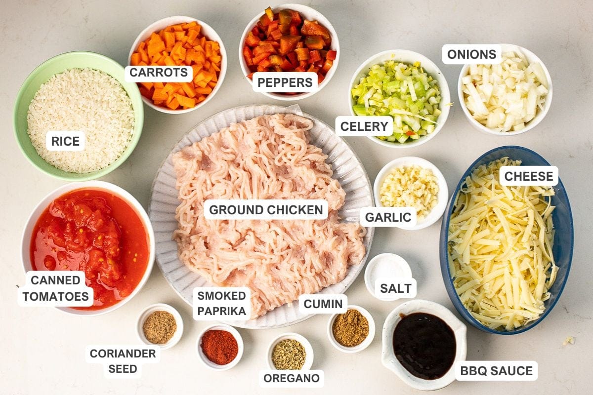 Ingredients for mexican chicken rice casserole including carrots, garlic, cumin, canned tomatoes, cheese, onions, and more.