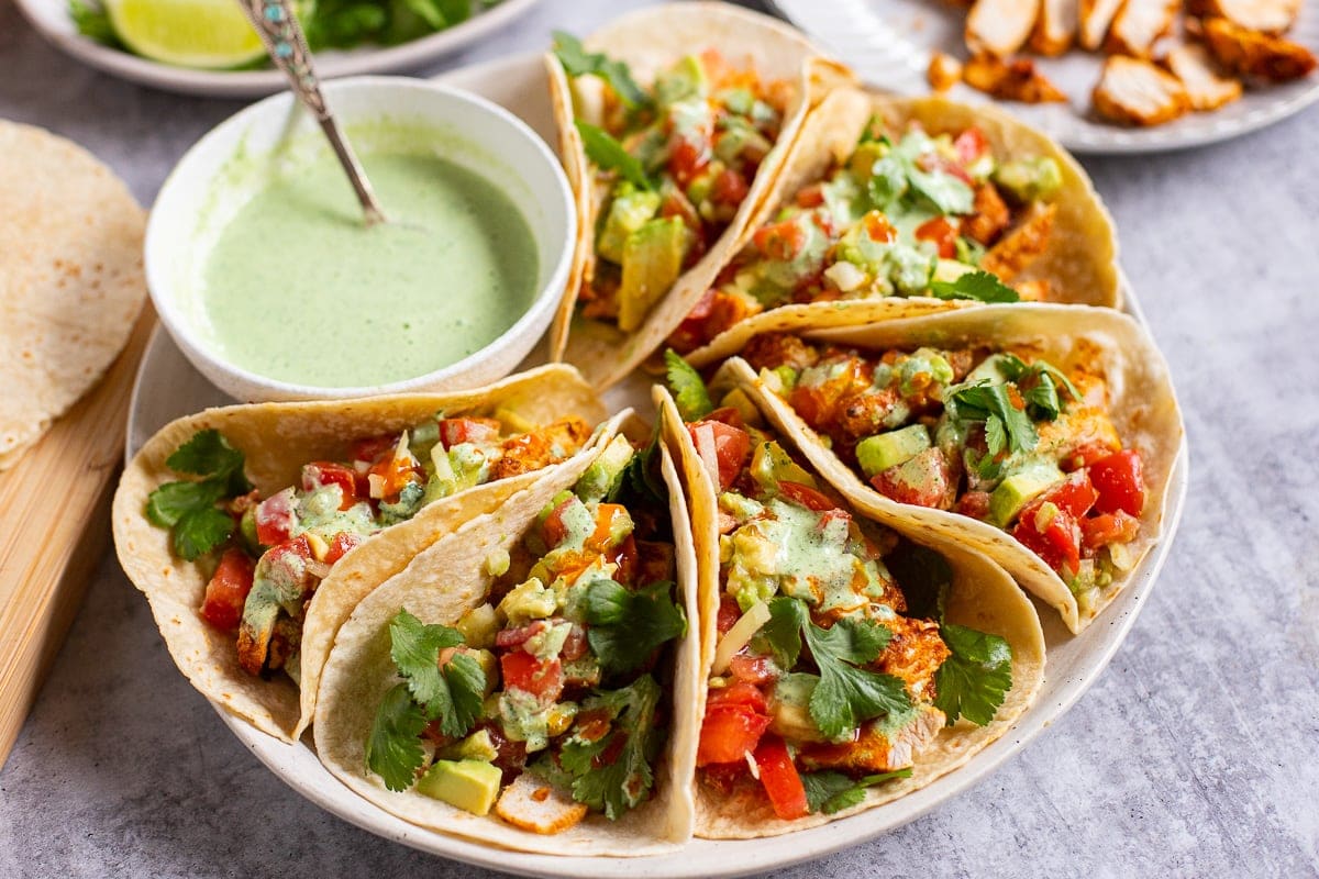 Healthy Chicken Tacos with cilantro sauce and avocado tomato salad.