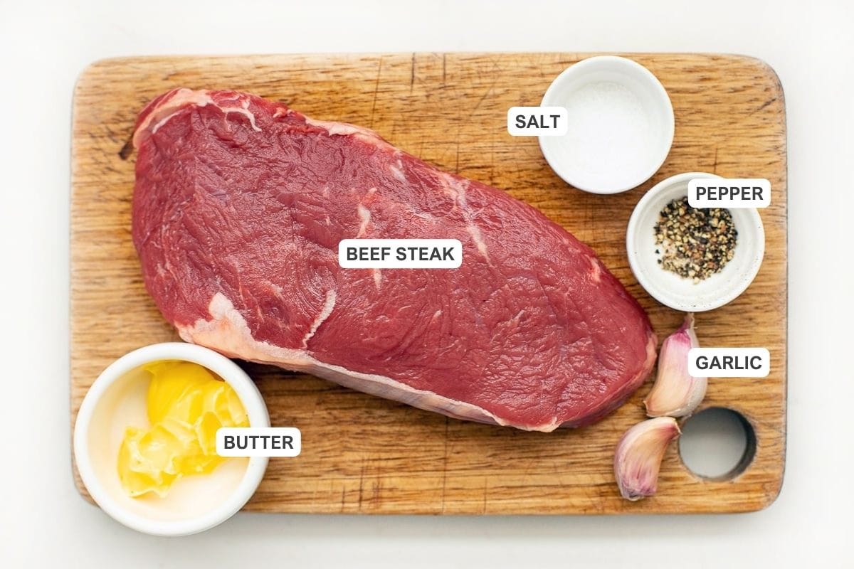 Ingredients for the recipe including steak, salt, pepper, butter, and cloves of garlic.