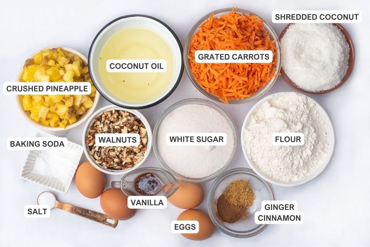 Ingredients for the recipe including all-purpose flour, baking soda, salt, ground cinnamon, ginger, white sugar, coconut oil, eggs, vanilla extract, carrots, pineapple, shredded coconut, and chopped walnuts.