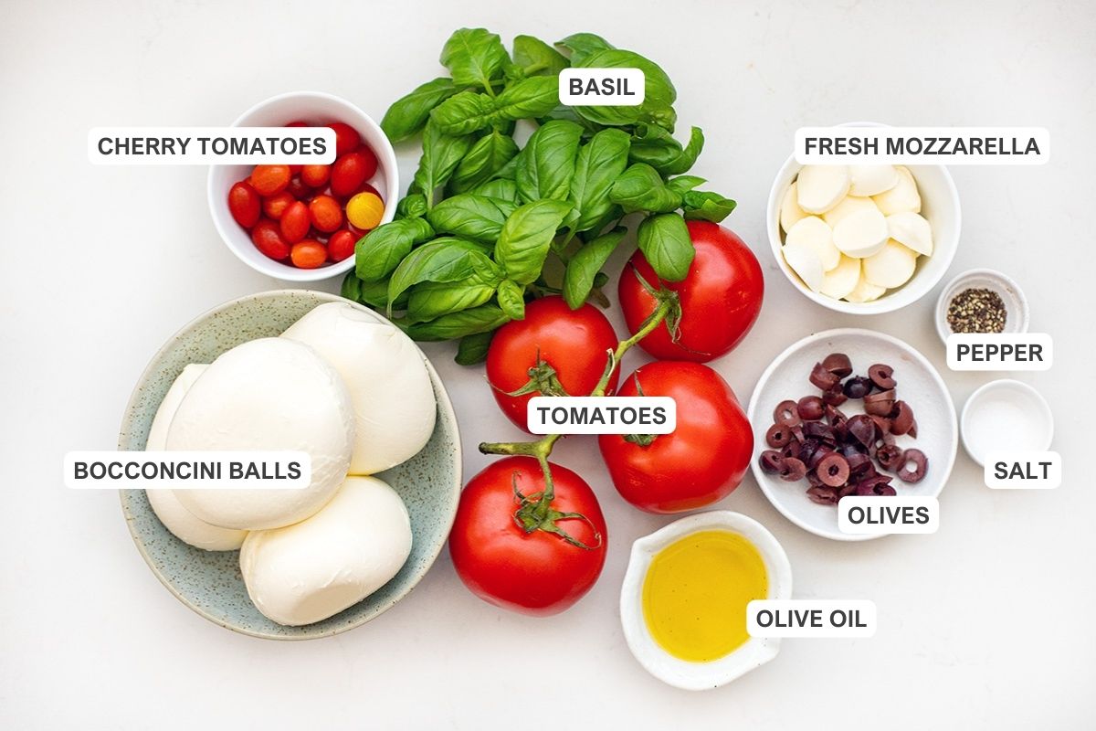 Ingredients for the recipe including bocconcini balls, cherry tomatoes, basil, tomatoes, fresh mozzarella, pepper, salt, olives, and olive oil.