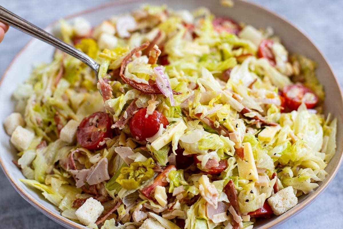 Chopped salad with lettuce, ham, salami, cherry tomatoes, pepperoncini and cheese.