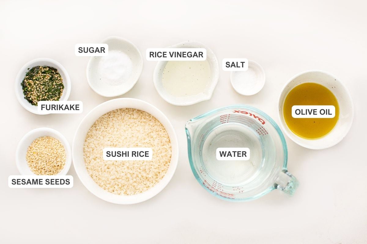 Ingredients for the recipe including sesame seeds, furikake, sushi rice, sugar, rice vinegar, water, salt, and olive oil.