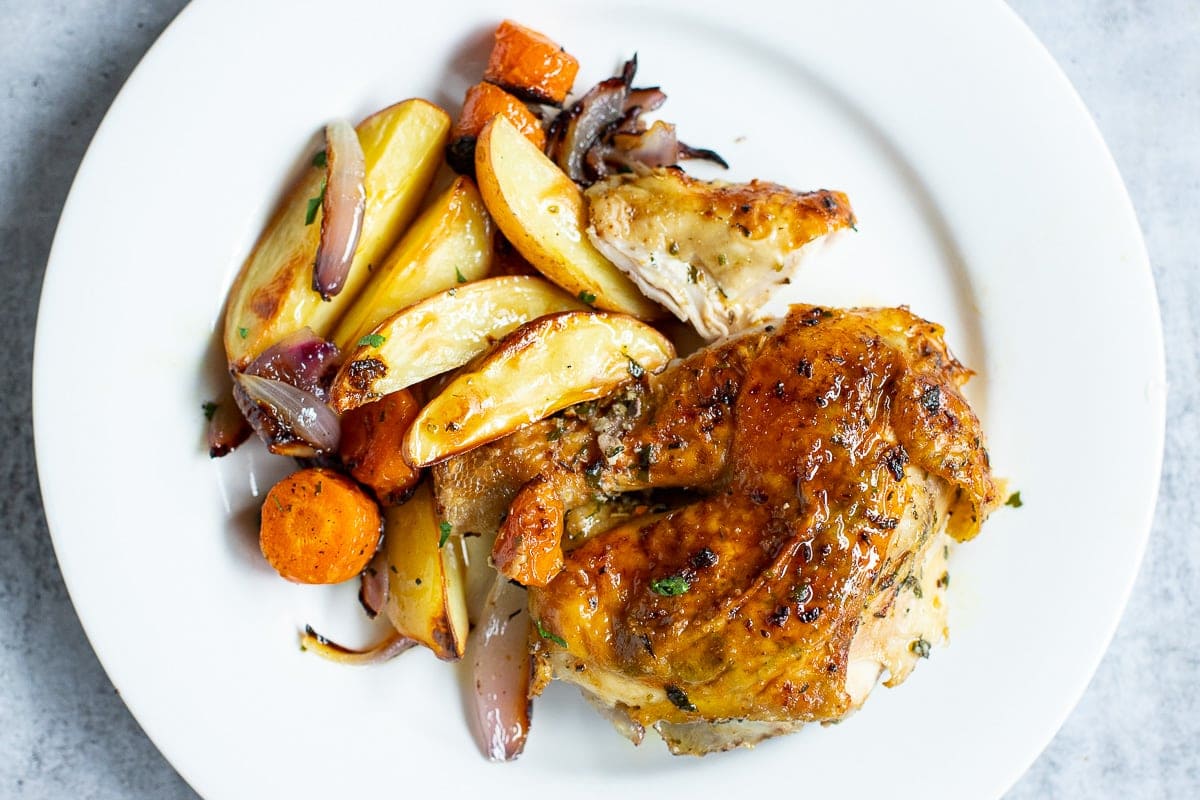 What to serve with spatchcock chicken: a piece of chicken thigh with potatoes, carrots, onions.