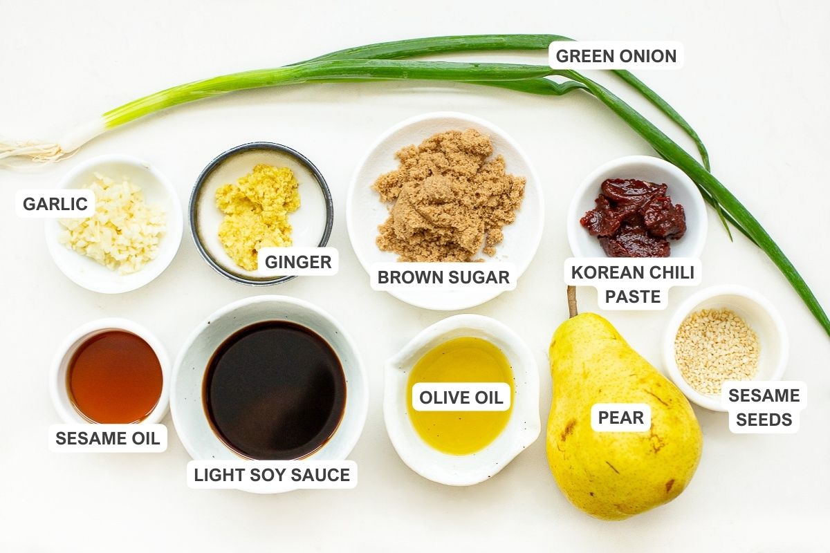 Ingredients for the recipe including garlic, ginger, brown sugar, korean chili paste, green onion, sesame oil, light soy sauce, olive oil, pear, and sesame seeds.