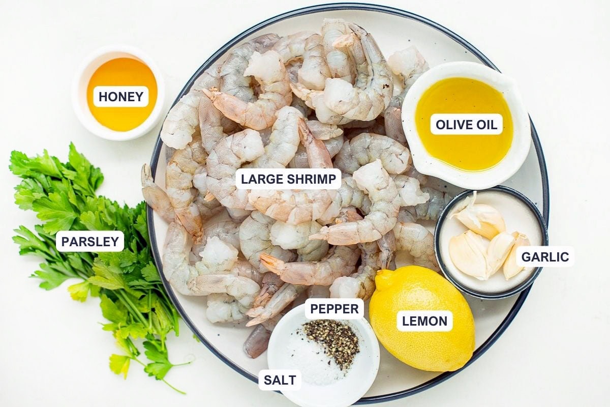 Ingredients for the recipe including large shrimp, olive oil, garlic, lemon, pepper, salt, honey, and parsley.